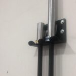Suporte de parede vertical para 2 barras olímpicas M1 Fitness instalado em academia